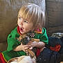 Angelica is registered to the contest to win money with this photo: toddler, child, puppy, dog, green_clothing, couch, blanket, happy, smiling, indoor, person, pet, cute, small_dog, holding, cozy, home, playing, expression, fun