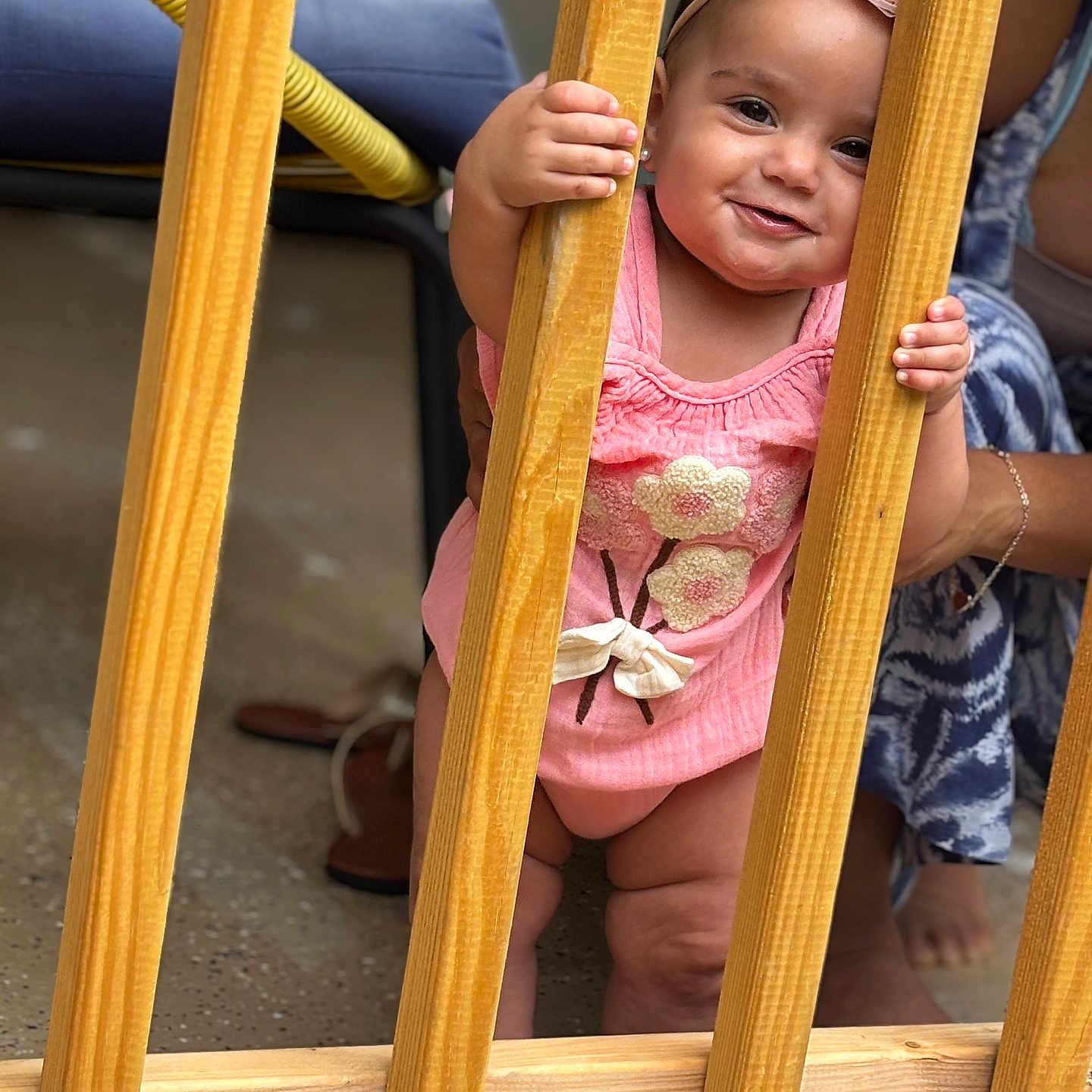 Heily joined the competition — help win amazing prizes! adult_hand, baby, child, curious, cute, floor, footwear, girl, happy, headband, holding, indoor, person, pink_clothing, playful, portrait, smiling, standing, support, wooden_slats