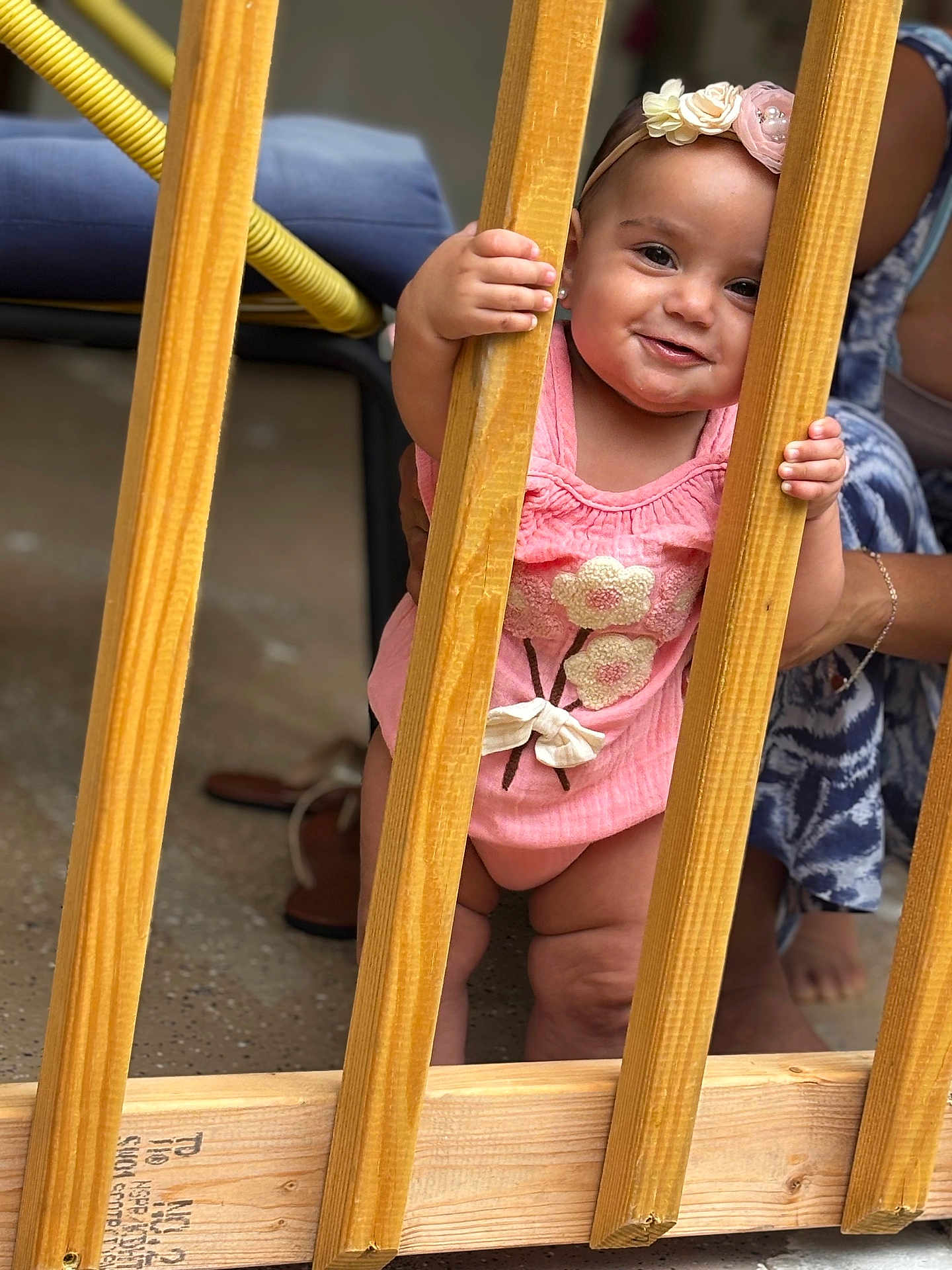 Heily joined the competition — help win amazing prizes! baby, child, girl, pink_clothing, headband, wooden_slats, smiling, holding, standing, adult_hand, indoor, floor, footwear, support, happy, cute, portrait, person, playful, curious