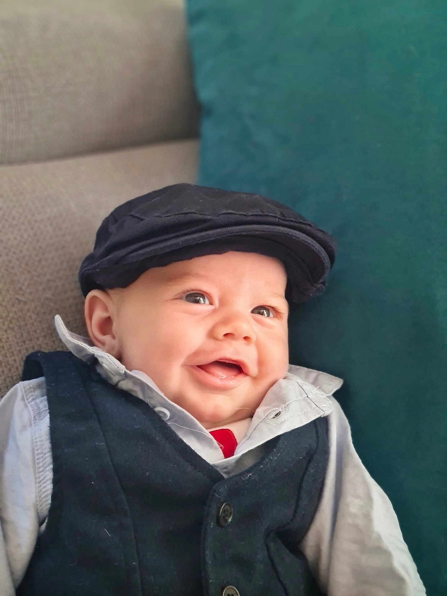Lyam a rejoint le concours — aidez-le/la à gagner de superbes lots ! baby, smiling, face, child, vest, cap, hat, clothing, happy, infant, portrait, cute, sitting, indoor, couch, pillow, person, headwear, fashion, young