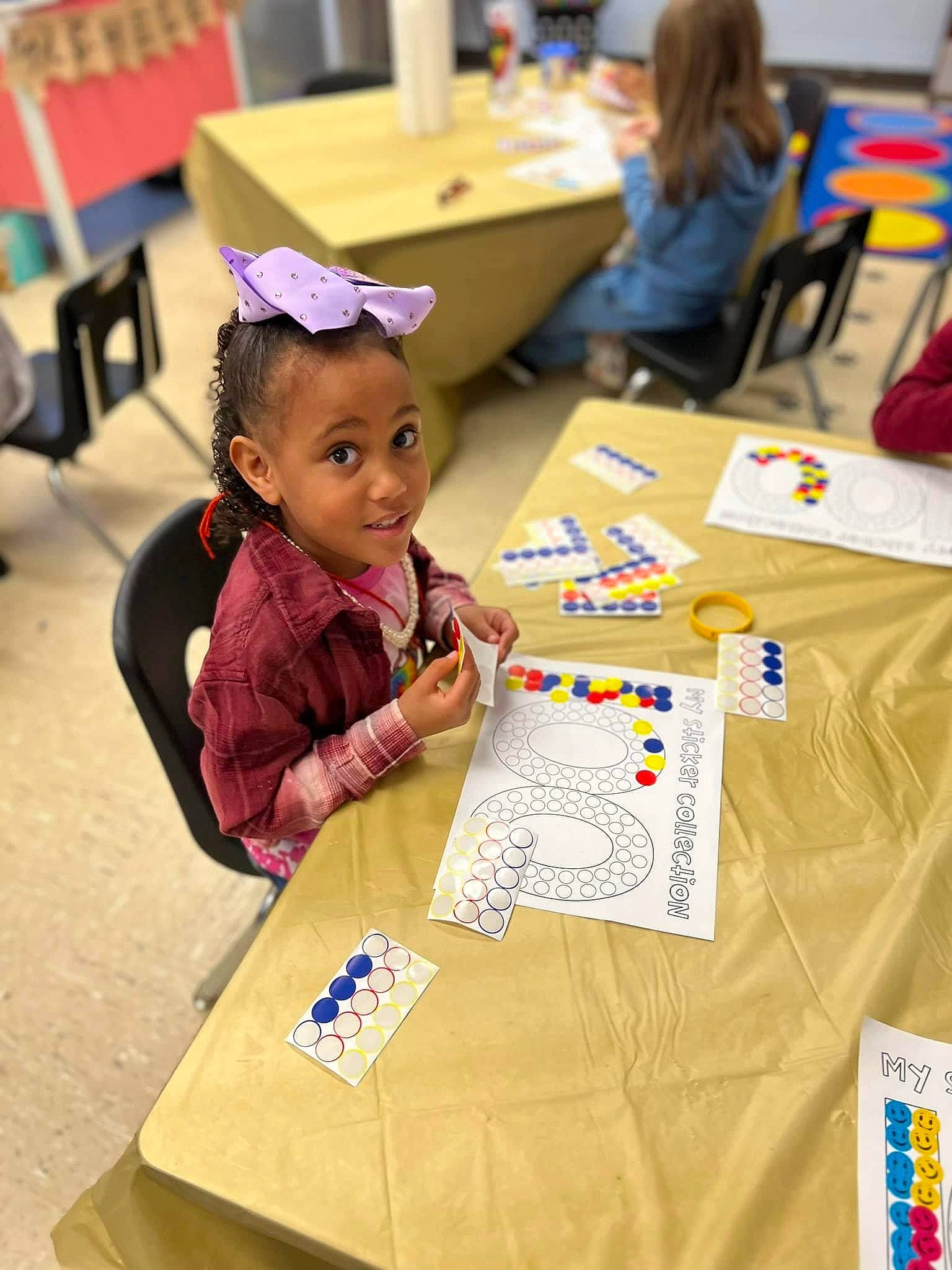 Olivia is registered to the contest to win money with this photo: adaptation, art, chair, child, desk, education, event, fun, furniture, kindergarten, learning, leisure, person, recreation, room, sharing, smile, t_shirt, table, toddler