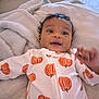 Dakotah is registered to the contest to win money with this photo: baby, infant, smiling, onesie, pumpkin_pattern, blanket, soft_texture, happy, cute, child, portrait, lying_down, indoors, cozy, warm, expression, face, head, small_hands, curly_hair