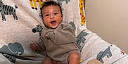 Dakotah is registered to the contest to win money with this photo: baby, infant, two_months, smiling, cute, blanket, animal_pattern, giraffe, elephant, toddler, clothing, sitting, indoor, happy, child, portrait, furniture, cozy, feet, cute_expression