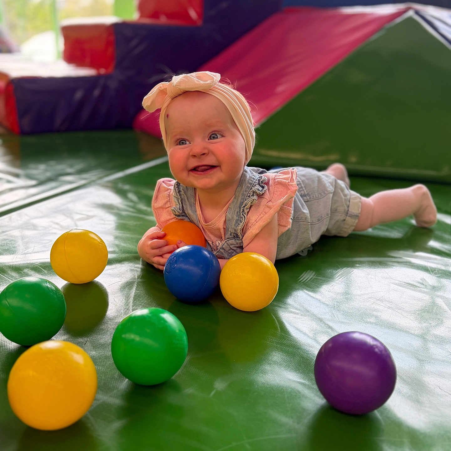Aimy participe au concours pour gagner de l'argent avec cette photo : baby, child, infant, headband, denim, pink, green_mat, colorful_balls, play_area, indoor, smiling, happy, cute, toddler, toy_balls, floor_play, person, portrait, playtime, fun