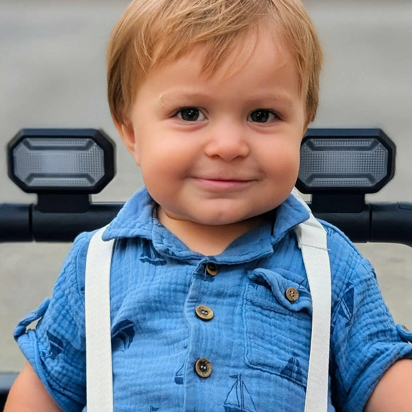 Malakai joined the competition — help win amazing prizes! baby, blue_shirt, buttoned_shirt, casual_clothing, child, closeup, cute, face, happy, light_brown_hair, outdoor, person, portrait, seatbelt, short_sleeves, smile, stroller, suspenders, toddler, young_child