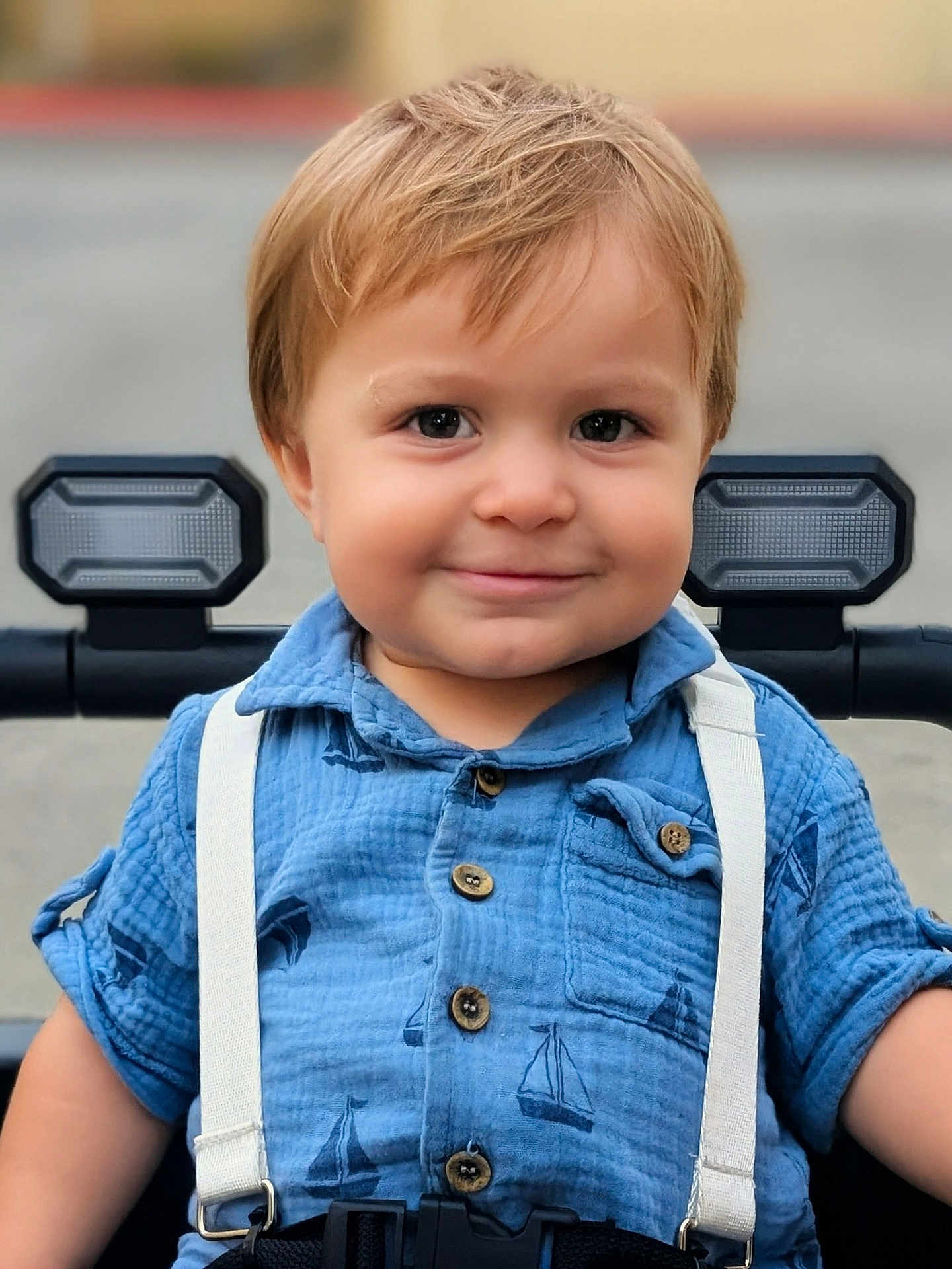 Malakai joined the competition — help win amazing prizes! toddler, child, smile, blue_shirt, suspenders, stroller, outdoor, face, buttoned_shirt, short_sleeves, light_brown_hair, happy, portrait, baby, young_child, cute, person, seatbelt, closeup, casual_clothing