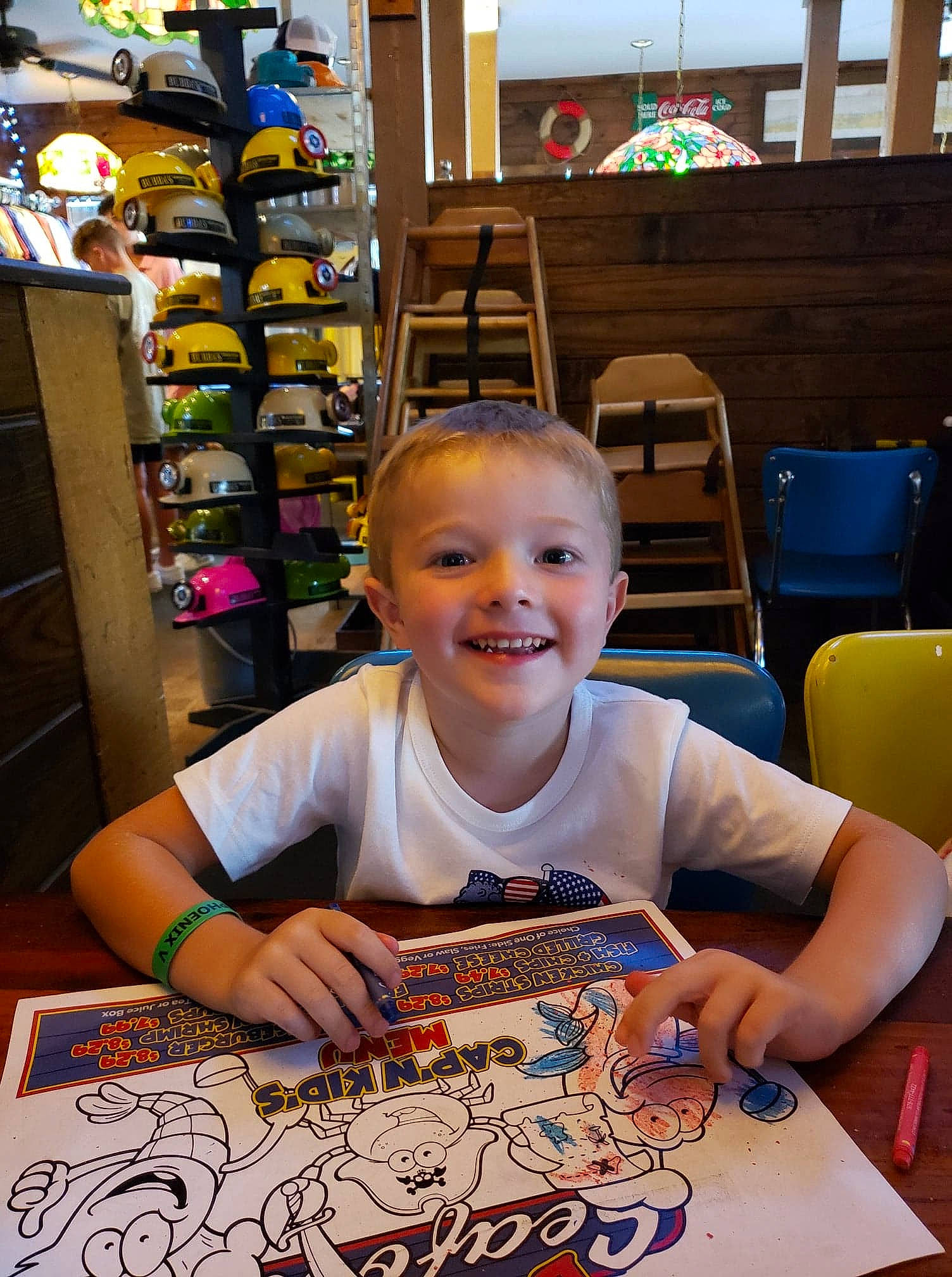 Braxton is registered to the contest to win money with this photo: art, artist, chair, child, event, fun, furniture, happy, indoor_games_and_sports, joy, leisure, person, recreation, room, shelf, shelving, smile, snapshot, t_shirt, table