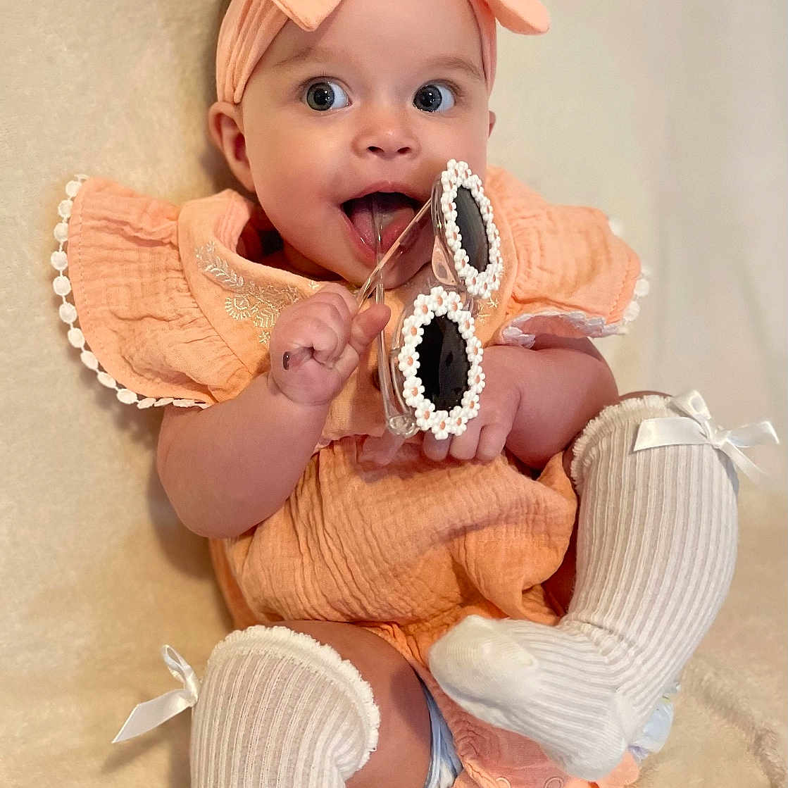 Valerie is registered to the contest to win money with this photo: baby, biting, bonnet, cap, clothing, costume, diaper, eating, face, food, footwear, hat, head, hosiery, person, photography, portrait, shoe, sitting, sock