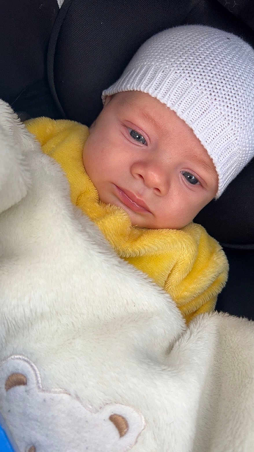 Keyron participe au concours pour gagner de l'argent avec cette photo : baby, infant, blanket, knit_hat, yellow_clothing, face, portrait, cozy, soft_texture, cute, child, wrapped, sleepy, warm, closeup, indoor, comfort, cushion, car_seat, adorable