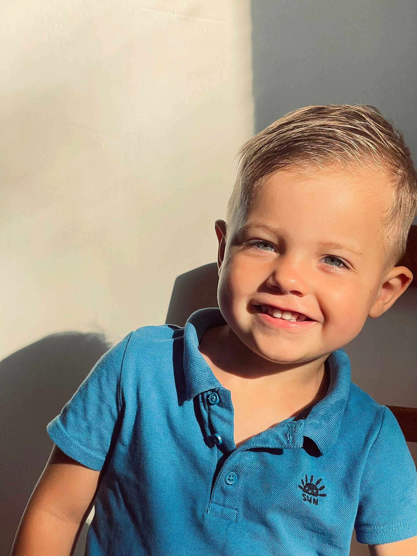 Nolan participe au concours pour gagner de l'argent avec cette photo : child, boy, smile, happy, blue_shirt, polo_shirt, short_sleeves, sunlight, shadow, portrait, indoor, face, hair, young_child, casual_clothing, closeup, light, skin, cute, person