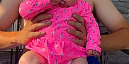 Josephine is registered to the contest to win money with this photo: baby, child, man, person, porch, sunlight, pink_pajamas, blue_shorts, flamingo_pattern, sitting, holding, thumb_sucking, outdoor, stone_wall, summer, casual_clothing, happy, family, portrait, skin