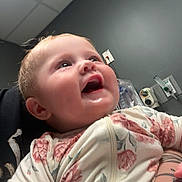 Josephine is registered to the contest to win money with this photo: baby, child, smiling, face, portrait, indoor, onesie, floral_pattern, tattoo, person, happy, infant, head, skin, cheeks, clothing, holding, wall, ceiling, room