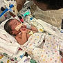 newborn, baby, hospital, medical_equipment, nicu, blanket, heart_pattern, infant, adult_hand, monitor, tubes, sensor, bed, care, patient, healthcare, resting, medical_care, person, hospital_room