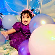 Rainelle joined the competition — help win amazing prizes! toddler, child, balloons, purple_dress, flower_headband, smiling, celebration, birthday, number_one, blue_backdrop, snowflakes, happy, indoors, festive, colorful, party, young_child, cute, joyful, portrait