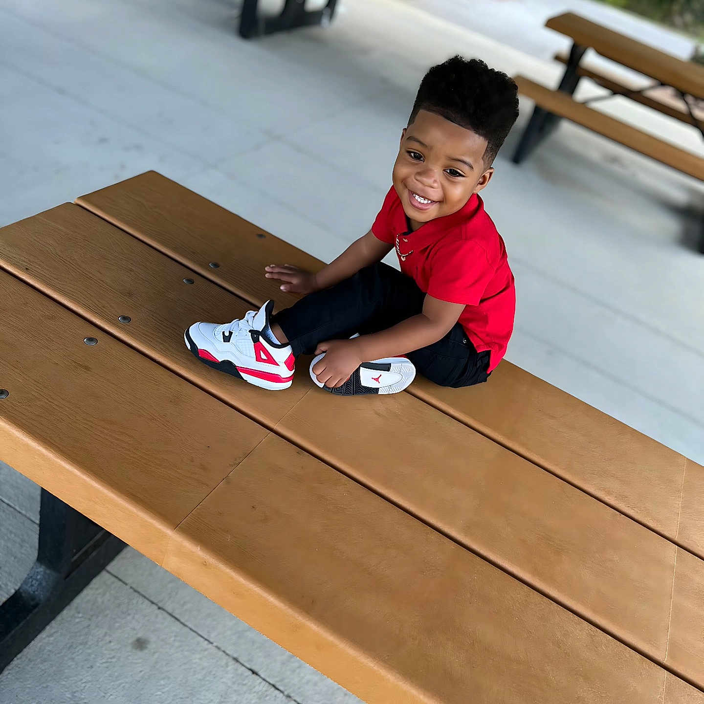 Kingston joined the competition — help win amazing prizes! black_pants, casual_clothing, child, concrete_floor, daylight, fun, greenery, happy, nature, outdoor, park, picnic_table, playing, portrait, red_shirt, seated, smiling, sneakers, wooden_table, young_boy