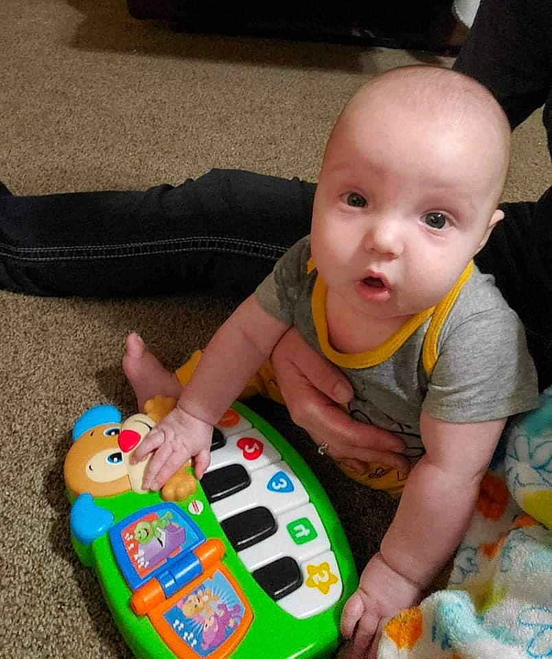 Jerry is registered to the contest to win money with this photo: arm, baby, baby_playing_with_toys, baby_products, baby_toddler_clothing, baby_toys, child, event, finger, flooring, fun, hand, lap, nail, person, play, sharing, sitting, toddler, toy