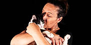 Fripon participe au concours pour gagner de l'argent avec cette photo : woman, cat, black_and_white_cat, hugging, kissing, affection, pet, animal, love, portrait, black_background, earrings, ring, skin, human, close_up, face, hands, feline, domestic_animal