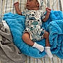 Aiden is registered to the contest to win money with this photo: baby, infant, blanket, bottle, clothing, dinosaur_pattern, hat, mattress, newborn, pattern, person, sock, soft_texture, toddler, lying_down, blue, white, feeding, resting, indoors