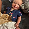 baby, child, infant, smiling, portrait, indoors, couch, stuffed_animal, elephant, lion, blanket, toy, clothing, usa_shirt, flag_pattern, blue_outfit, cozy, sitting, happy, close_up