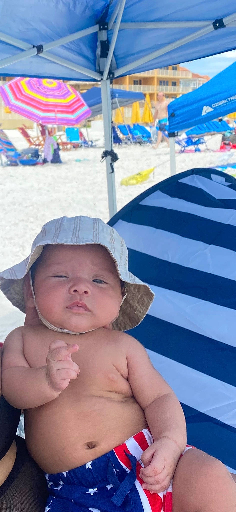 Leonidas is registered to the contest to win money with this photo: baby, black, blue, fun, gesture, happy, hat, headgear, headwear, leisure, people_on_beach, person, photograph, product, recreation, shade, skin, summer, sun_hat, toddler