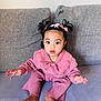 toddler, child, baby, pink_clothing, knitwear, couch, sofa, indoor, portrait, cute, curly_hair, ponytails, bows, sitting, expression, hands, face, eyes, socks, cozy