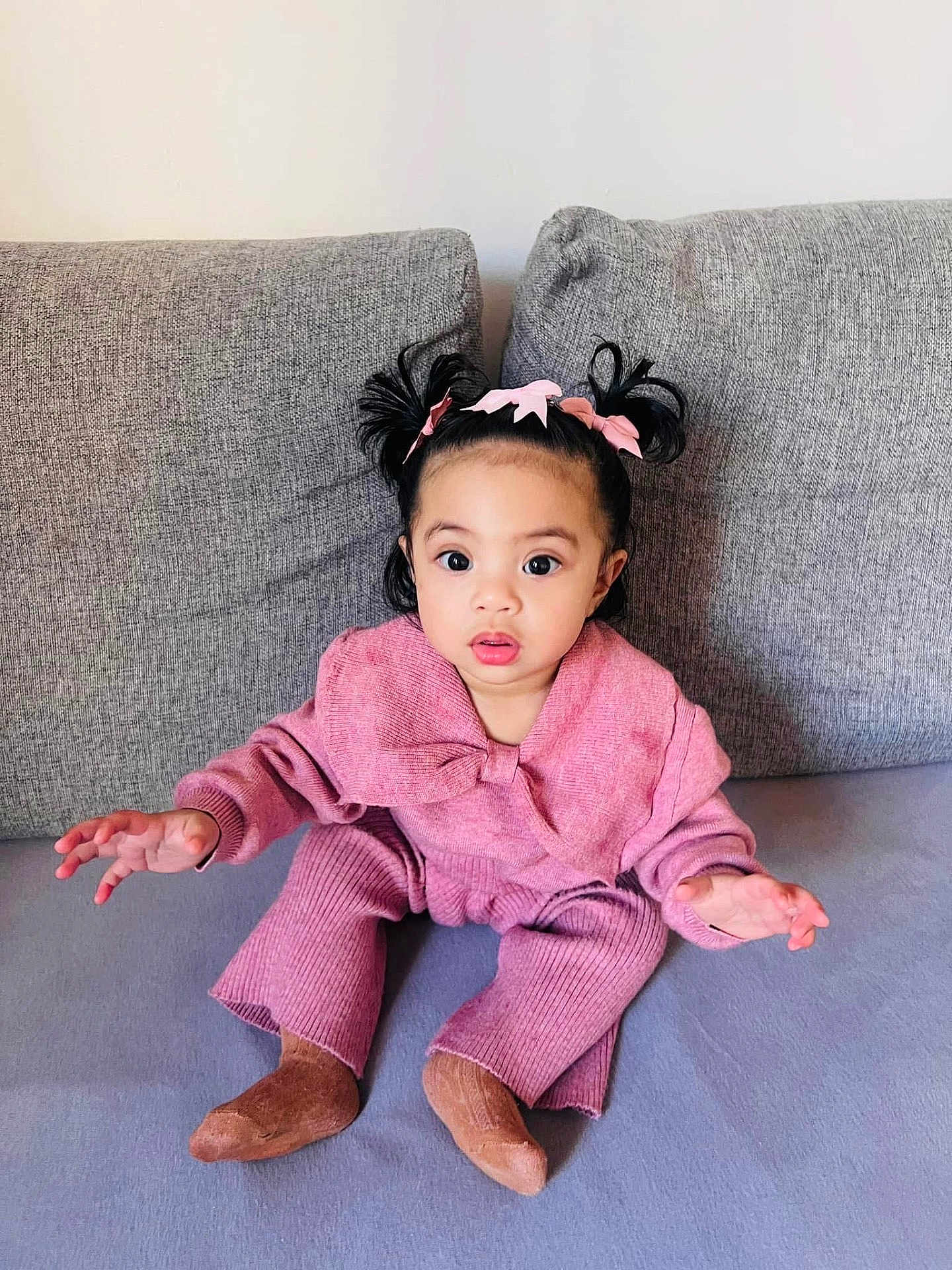 Tamarah Luna a rejoint le concours — aidez-le/la à gagner de superbes lots ! toddler, child, baby, pink_clothing, knitwear, couch, sofa, indoor, portrait, cute, curly_hair, ponytails, bows, sitting, expression, hands, face, eyes, socks, cozy