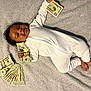 baby, infant, money, twenty_dollar_bills, onesie, blanket, smiling, lying_down, hand, foot, currency, cash, cute, indoors, child, person, happy, small, finance, rich