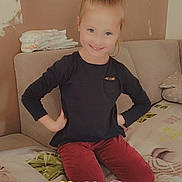 Steffy participe au concours pour gagner de l'argent avec cette photo : bed, casual_clothing, child, cozy, cute, girl, happy, heart_emojis, home, indoors, long_sleeve, love_text, paint_patches, pillow, pony_tail, portrait, red_pants, seated, smiling, wall