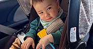 Eli is registered to the contest to win money with this photo: toddler, child, car_seat, car_interior, seatbelt, clothing, socks, pants, toy, canopy, window, sunlight, face, hands, sitting, baby, cute, infant, safety, vehicle