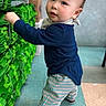 Eli is registered to the contest to win money with this photo: toddler, child, striped_pants, navy_shirt, curious, green_items, stacked_objects, indoor, floor_tiles, standing, person, face, short_hair, sneakers, playful, bright_colors, young_child, exploring, casual_clothing, background_blur