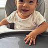 baby, child, high_chair, smiling, onesie, teddy_bear_print, hand, tray, indoor, window_blinds, happy, cute, infant, face, young_child, portrait, small_hand, eager, light, shadow