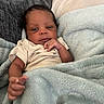 Dallas is registered to the contest to win money with this photo: baby, infant, blanket, couch, pillow, soft_texture, curly_hair, skin, hand, clothing, indoors, portrait, relaxing, comfortable, young_child, person, face, expression, resting, cozy