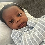 Dallas is registered to the contest to win money with this photo: baby, child, close_up, cozy, curly_hair, cute, expression, eyes, face, indoors, infant, newborn, person, pillow, portrait, resting, skin, soft_texture, striped_clothing, young