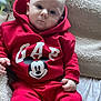 baby, infant, red_clothing, hoodie, mickey_mouse, gap_brand, blanket, milk_bottle, hand, face, expressionless, sitting, indoors, soft_texture, child, cute, young, portrait, cozy, casual