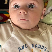 Nolan joined the competition — help win amazing prizes! baby, infant, face, eyes, expression, shirt, clothing, sun_graphic, text, blanket, cute, portrait, closeup, skin, head, person, child, laying, indoors, young