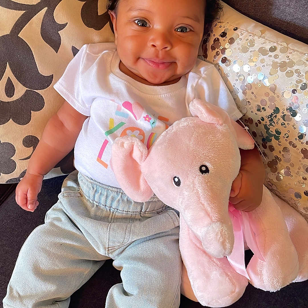 Kalíah Ezell joined the competition — help win amazing prizes! baby, clothing, couch, cushion, face, footwear, furniture, happy, head, homedecor, jeans, pants, person, photography, portrait, shoe, sitting, smile, teddybear, toy