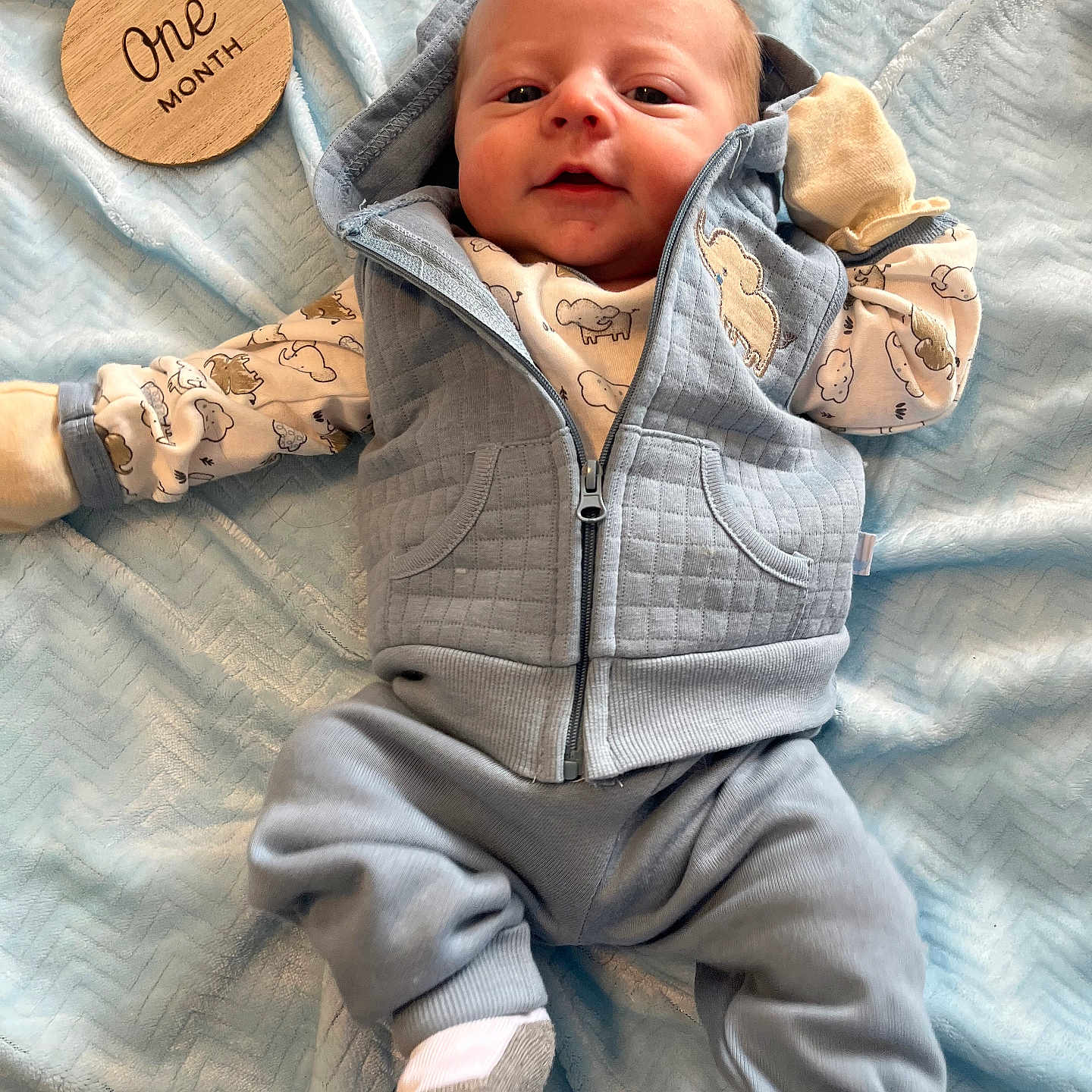 Ethan is registered to the contest to win money with this photo: baby, blanket, clothing, coat, face, hat, head, hood, hoodie, hosiery, jacket, knitwear, newborn, pants, person, photography, portrait, sock, sweater, sweatshirt