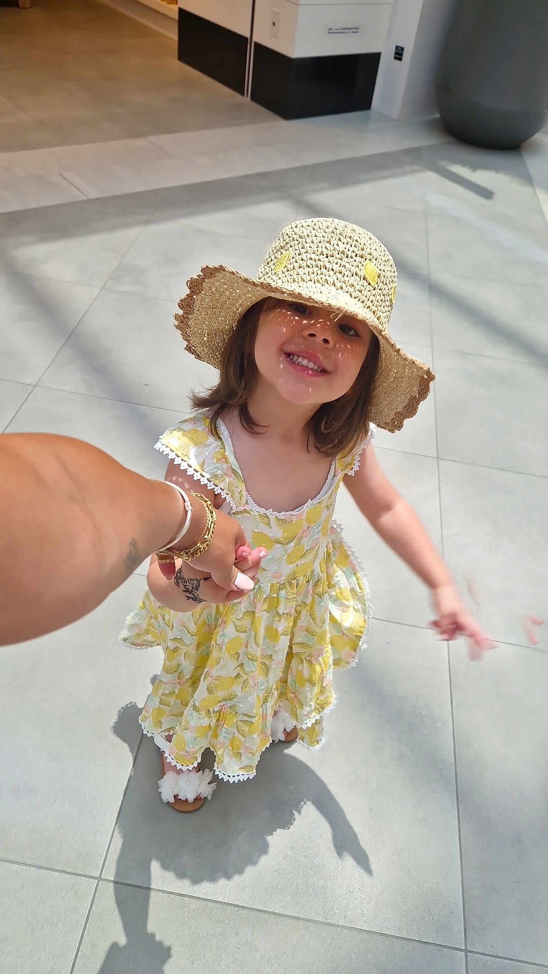 Remy participe au concours pour gagner de l'argent avec cette photo : child, girl, smiling, hat, straw_hat, yellow_dress, holding_hands, sunlight, shadow, indoor, tile_floor, footwear, sandal, happy, portrait, person, cute, summer, fashion, hand