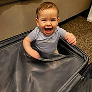 Ryan a rejoint le concours — aidez-le/la à gagner de superbes lots ! toddler, child, smiling, suitcase, indoor, carpet, couch, happy, playing, young_child, person, clothing, short_sleeve, brown_hair, face, mouth_open, cheerful, living_room, fabric, seat
