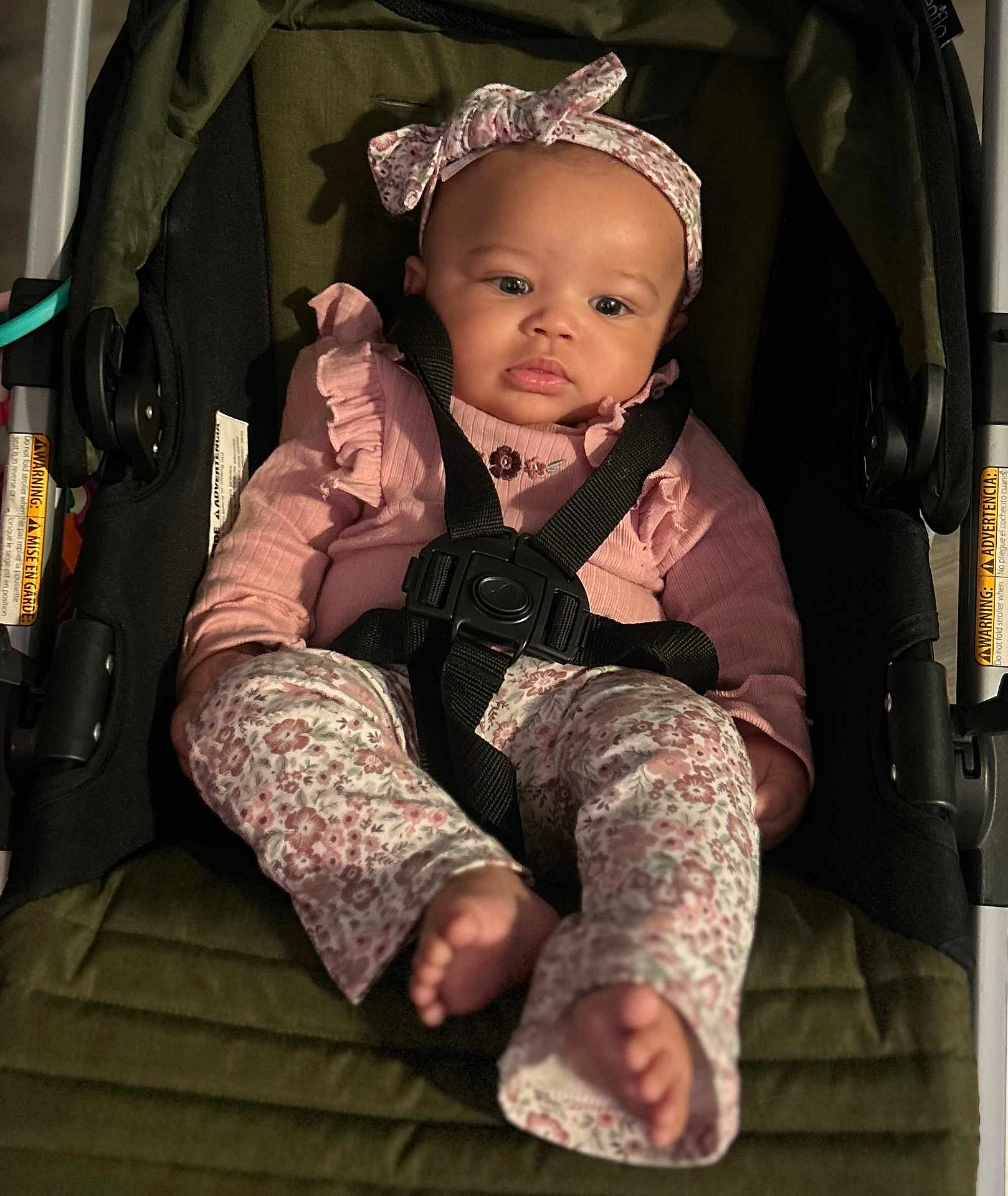 Dominique is registered to the contest to win money with this photo: baby, child, car_seat, seatbelt, pink_clothing, headband, bow, floral_pattern, infant, cute, portrait, indoor, sitting, clothing, footwear, person, young_child, baby_girl, comfort, safety