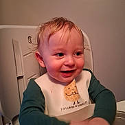 Onyx is registered to the contest to win money with this photo: baby, bib, blond_hair, child, clothing, cute, expression, face, feeding, happy, high_chair, indoor, messy_hair, person, portrait, sitting, smiling, table, toddler, young