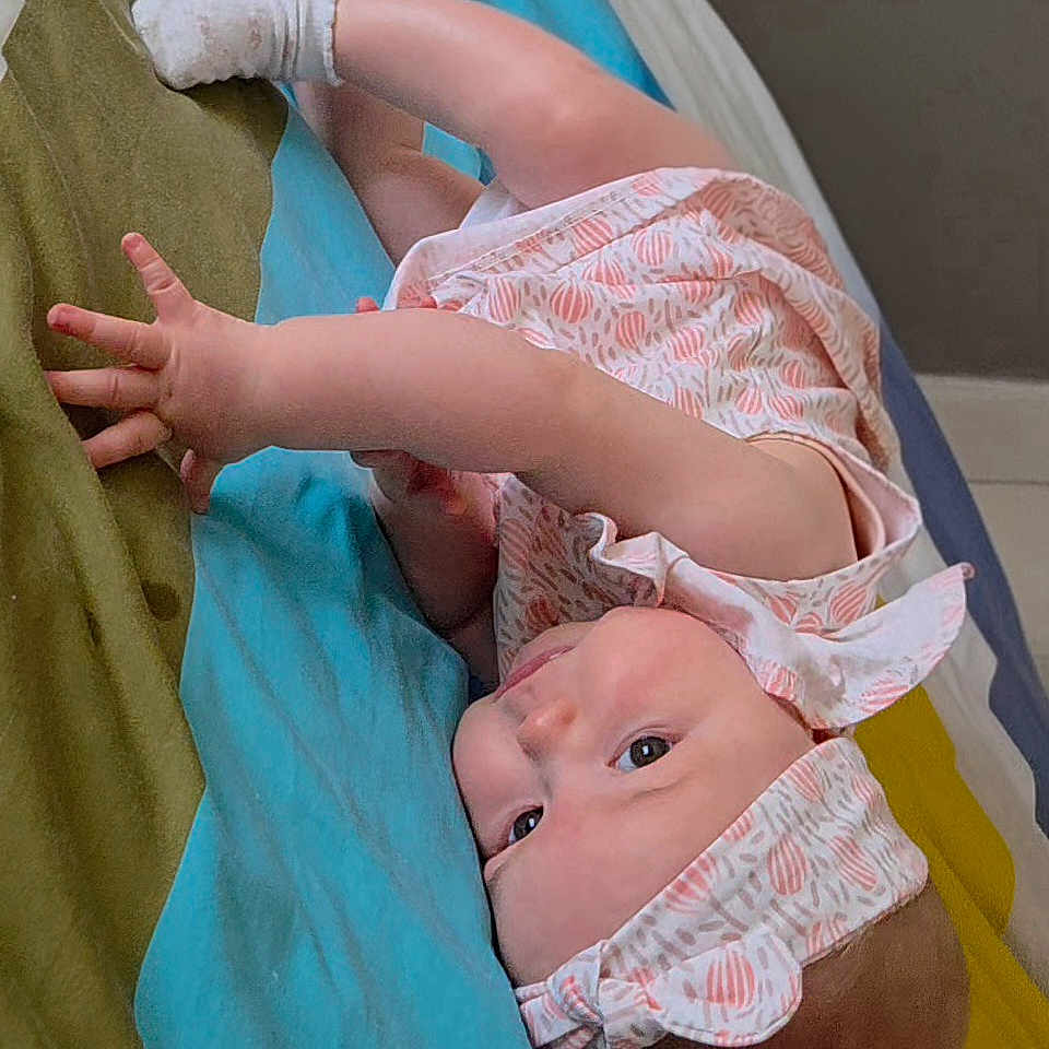 Victoire participe au concours pour gagner de l'argent avec cette photo : baby, infant, headband, socks, blanket, striped_blanket, lying_down, curious, child, cute, indoors, person, reaching_hand, soft_lighting, colorful, bed, toddler, wearing_clothes, skin, portrait