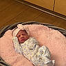 Raelyn is registered to the contest to win money with this photo: baby, newborn, sleeping, basket, blanket, pink, headband, onesie, floor, wooden_floor, indoors, cozy, infant, soft_texture, sleep, cute, resting, child, person, wearing