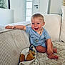 baby, child, smiling, blue_onesie, couch, stuffed_toy, plush_dog, happy, indoor, living_room, soft_texture, blanket, cute, toddler, playful, sitting, armrest, light, portrait, home