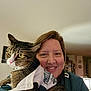 Spruce is registered to the contest to win money with this photo: animal, casual, cat, clothing, cozy, domestic_animal, face, feline, happy, holding, home, indoor, living_room, person, pet, portrait, smiling, sports_jersey, tabby_cat, woman