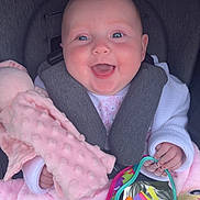 Hallie is registered to the contest to win money with this photo: baby, smiling, car_seat, toy, mirror, plush_toy, pink_blanket, white_clothing, happy, child, infant, seatbelt, colorful, hand, face, closeup, indoors, cute, soft_texture, joy