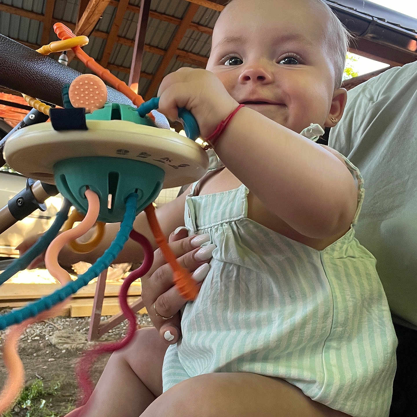 Celine joined the competition — help win amazing prizes! baby, child, earrings, fingers, grass, greenery, hand, happy, outdoor, person, playtime, romper, seat, smile, striped_clothing, sunlight, support, tentacles, toy, wooden_structure