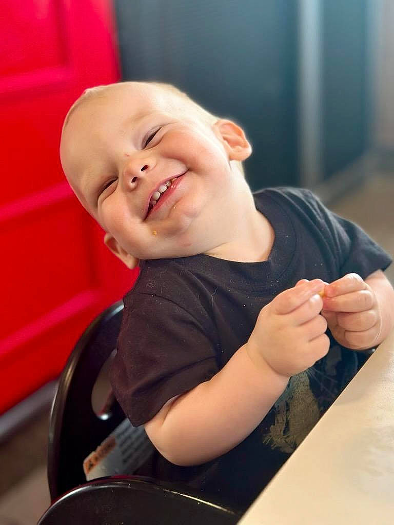 William is registered to the contest to win money with this photo: baby, baby_toddler_clothing, chair, child, chin, comfort, eye, facial_expression, finger, fun, gesture, hand, happy, human_body, joy, mouth, person, skin, sleeve, smile
