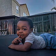 Brixxton joined the competition — help win amazing prizes! backyard, blue_pants, child, clothing, curious, daylight, fence, grass, house, outdoor, person, play, portrait, sky, smile, striped_shirt, toddler, trampoline, wood, young