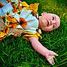 Lillie is registered to the contest to win money with this photo: arm, baby, blue_eyes, bright, child, colorful, cute, dress, grass, greenery, infant, laying, nature, outdoor, playful, portrait, relaxed, skin, summer, sunflower